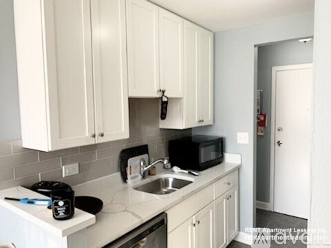A kitchen with white cabinets and a black pot on the stove.