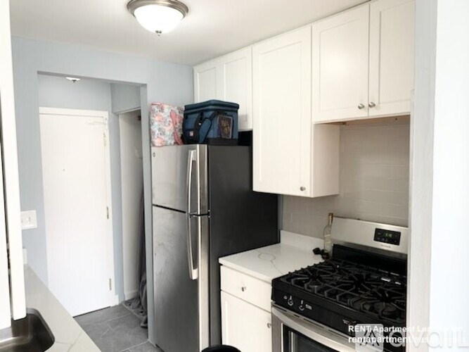 A kitchen with a black fridge and stove top oven.