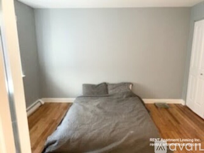 A bedroom with a bed covered in a grey blanket.