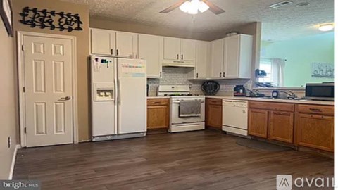 A kitchen with white appliances and wooden cabinets.