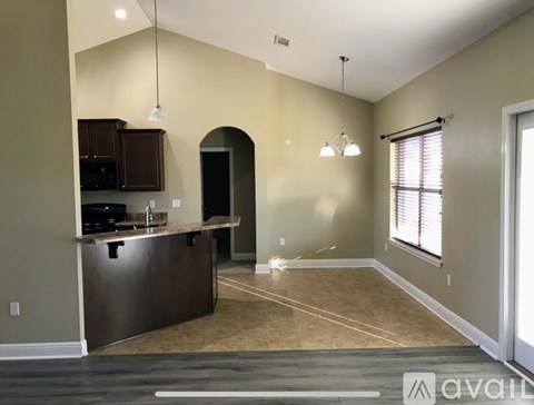 A spacious kitchen with a bar counter and a window with blinds.
