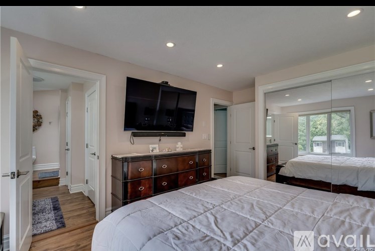 A bedroom with a large bed and a flat screen TV mounted on the wall.