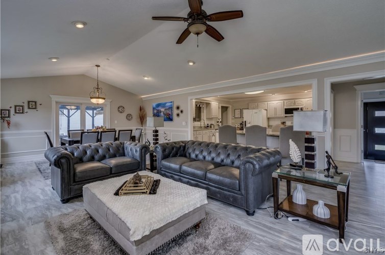 A living room with a black leather couch and a grey rug.