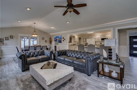 A living room with a black leather couch and a grey rug.