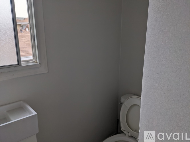 A white toilet in a small bathroom with a window.