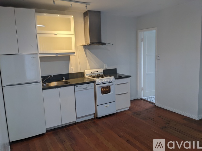 A kitchen with white cabinets and a wooden floor.