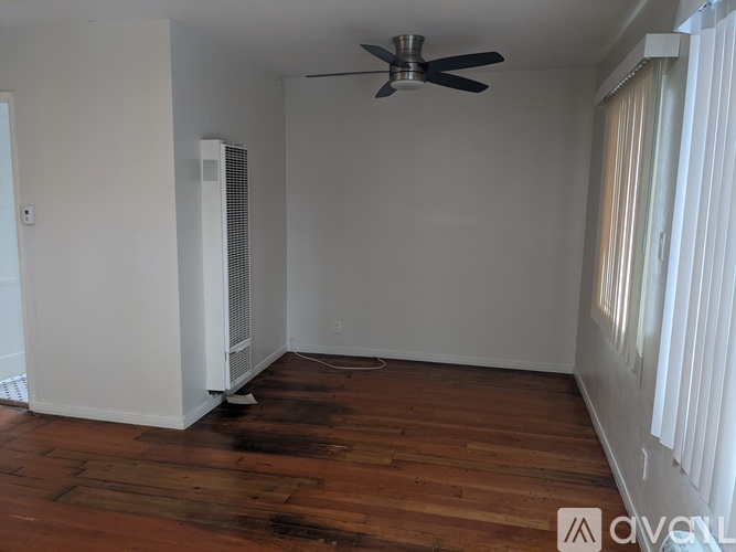 A room with a ceiling fan and a window with blinds.