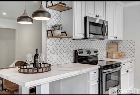 A kitchen with white cabinets and a white island with a wine glass holder.
