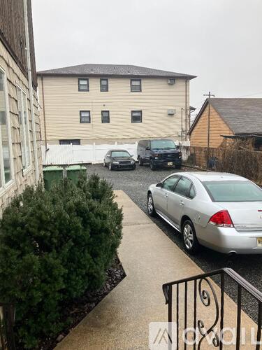 A silver car is parked on a driveway in front of a house.