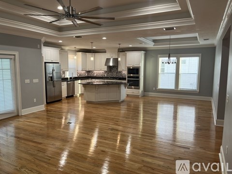 A spacious kitchen with wooden floors and a ceiling fan.