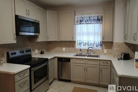 A kitchen with a black stove top oven and a black microwave above a white counter.