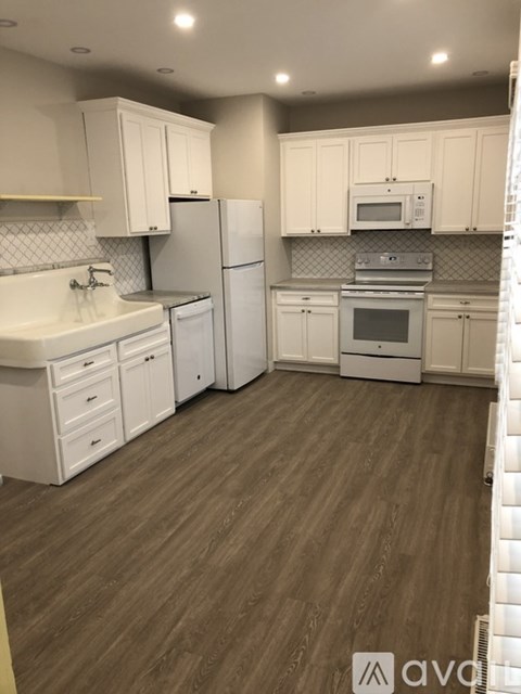 A kitchen with white cabinets and appliances.