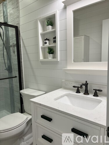 A white bathroom with a toilet, sink, and mirror.