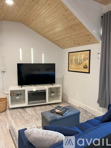 A living room with a blue couch and a television on a white stand.