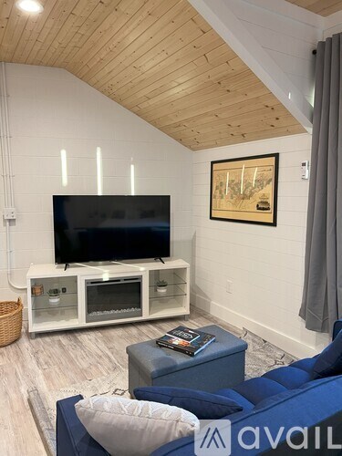 A living room with a blue couch and a television on a white stand.