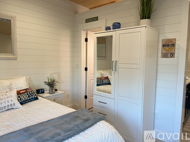 A bedroom with a bed, a nightstand, and a cabinet with a mirror above it.