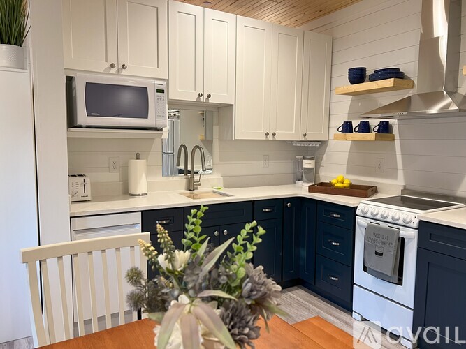 A kitchen with white cabinets and a white microwave.