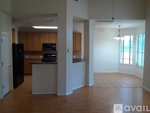 A kitchen with wooden cabinets and a black refrigerator.