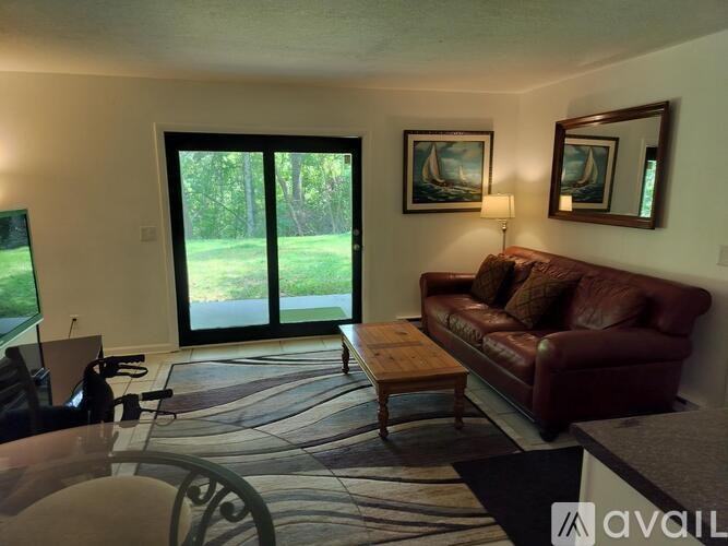 A living room with a red couch, a coffee table, and a painting of a sailboat on the wall.