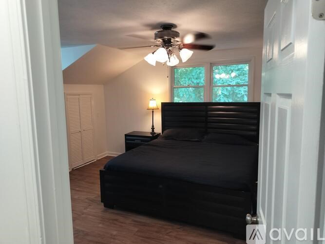 A bedroom with a black bed and a ceiling fan.
