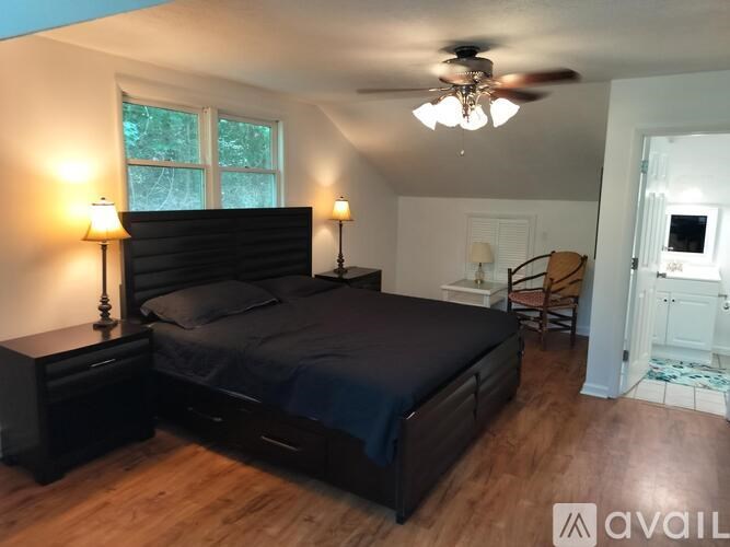 A bedroom with a bed, two lamps, and a ceiling fan.