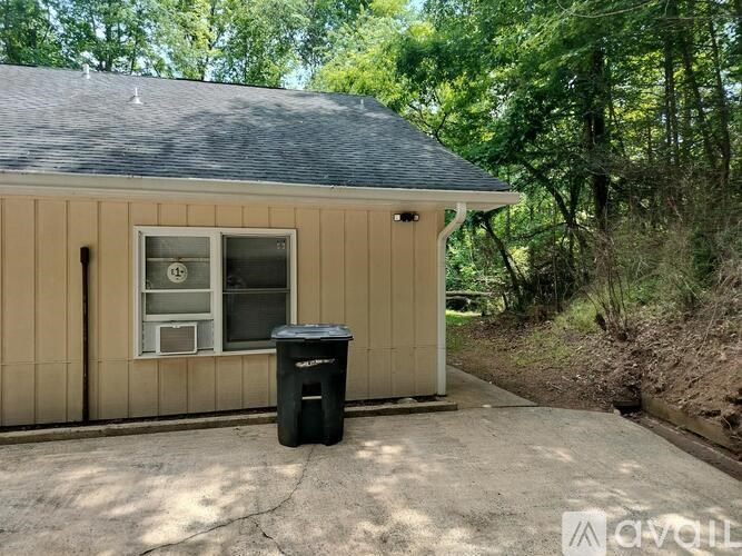 A small building with a black trash can in front of it.