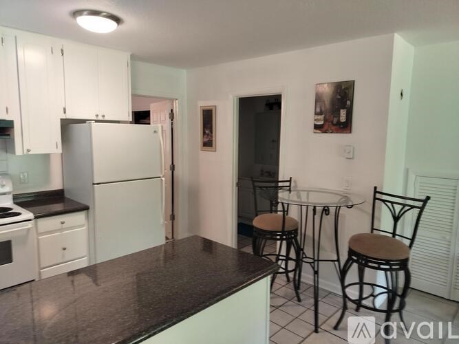 A kitchen with white cabinets and a black countertop.