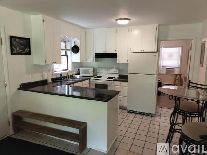 A kitchen with white cabinets and black countertops.