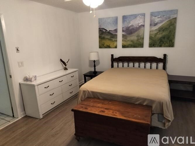 A bedroom with a bed, nightstand, and a painting on the wall.