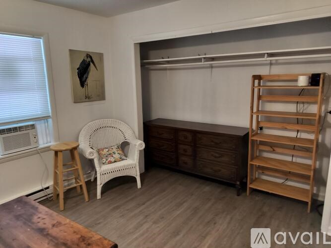 A room with a white chair, a wooden cabinet, and a wooden shelf.