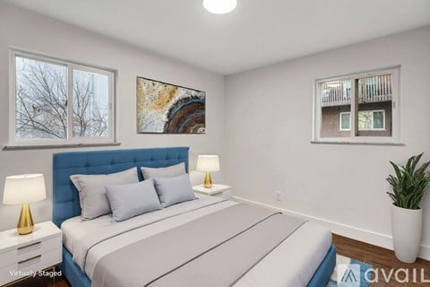 A bedroom with a large bed, two lamps, and a painting on the wall.