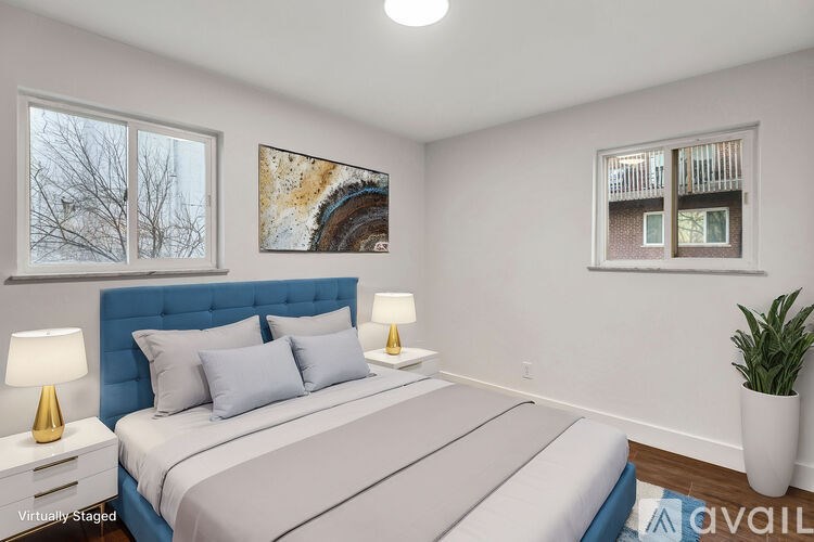 A bedroom with a large bed, two lamps, and a painting on the wall.