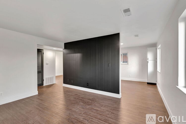 A spacious room with wooden flooring and a large black wall.