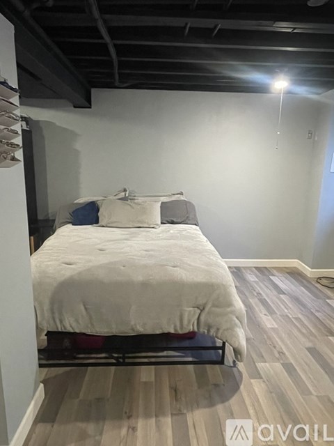 A bedroom with a bed and a wooden floor.
