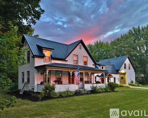 A house with a flag on the porch is available for sale.