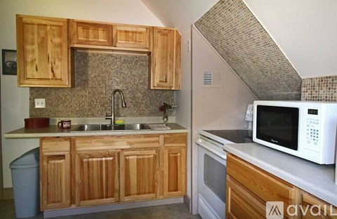 A kitchen with wooden cabinets and a white microwave.