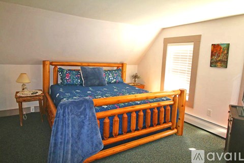 A bedroom with a bed, nightstand, and window.