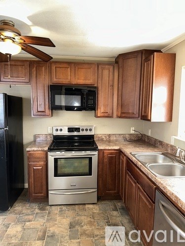 A kitchen with wooden cabinets and a black refrigerator.