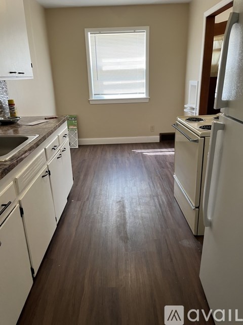 A kitchen with white cabinets and a wooden floor.