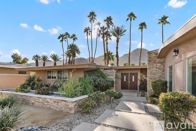 A house with a front yard and palm trees.