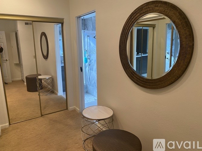 A round mirror hangs on a wall above a small stool.