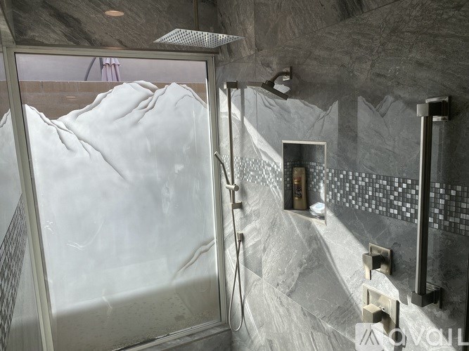 A bathroom with a glass shower door and a marble wall.