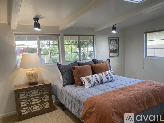 A bedroom with a bed, pillows, a lamp, and a ceiling fan.