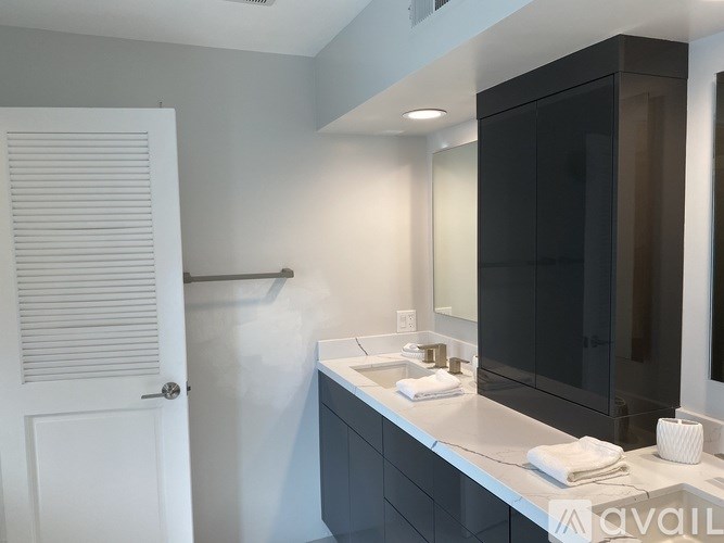 A bathroom with a white door, a sink, and a mirror.