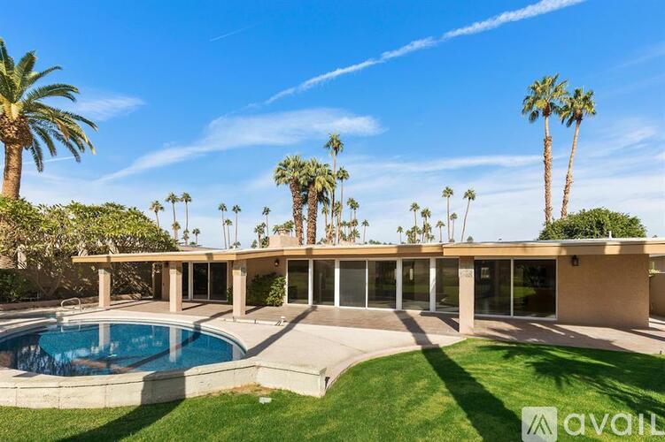 A house with a pool and palm trees in the background.