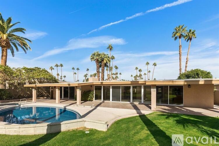 A house with a pool and palm trees in the background.