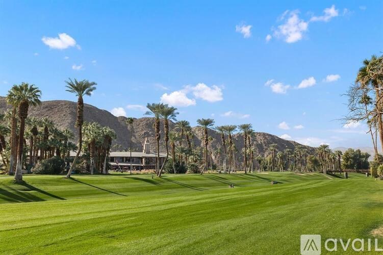 A golf course with palm trees and a mountain in the background.