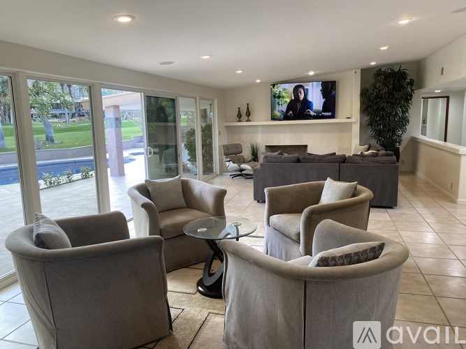 A living room with a television on the wall and a glass table in the middle.