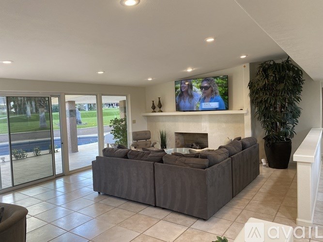 A living room with a grey couch and a flat screen TV mounted on the wall.