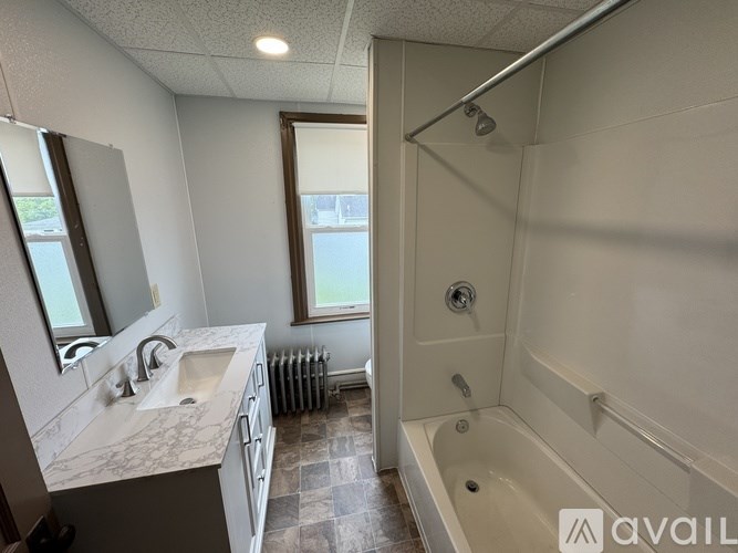 A bathroom with a tub, sink, and mirror.
